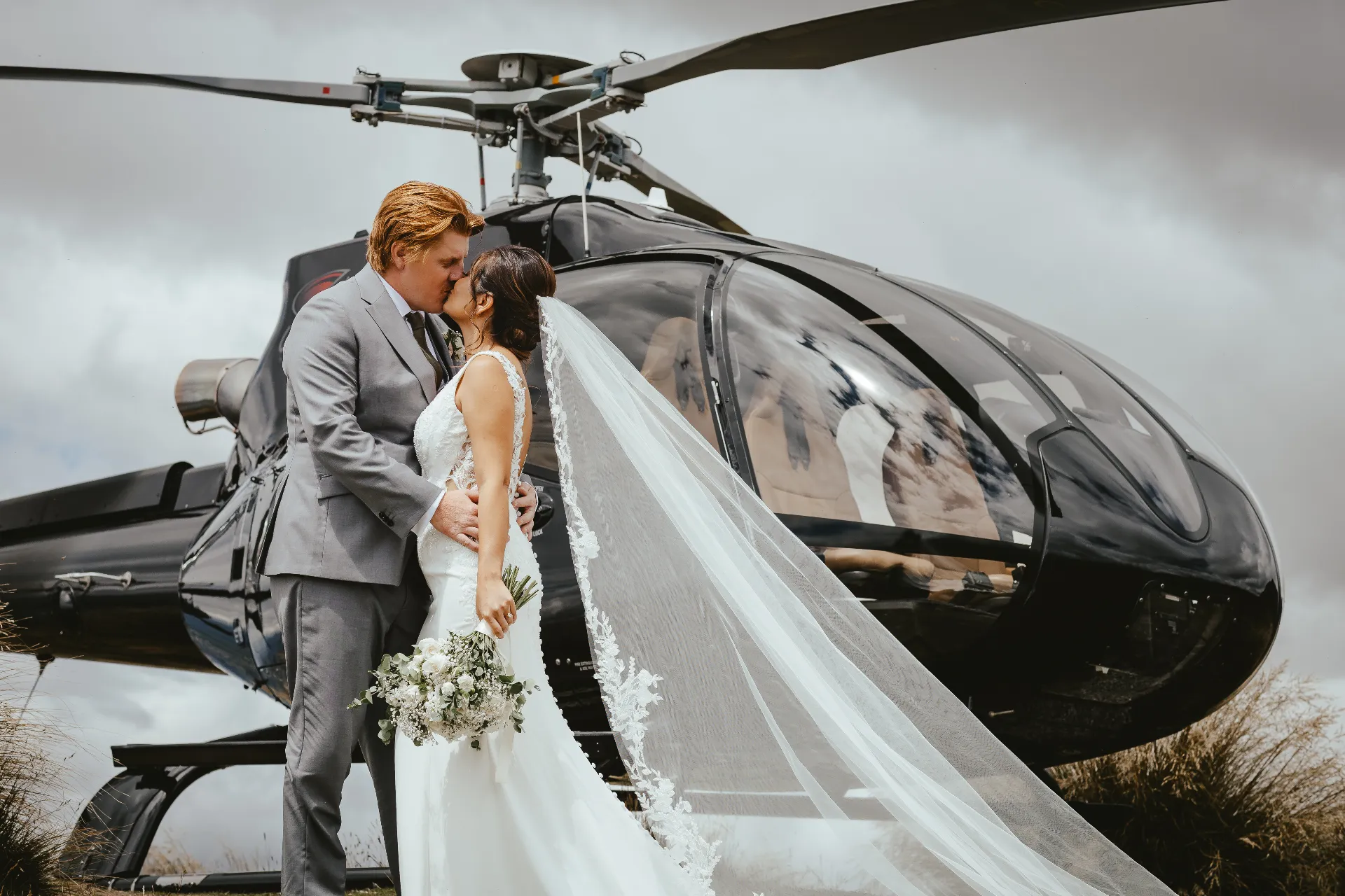 Couple kissing beside a helicopter at Coromandel Peak, Wānaka